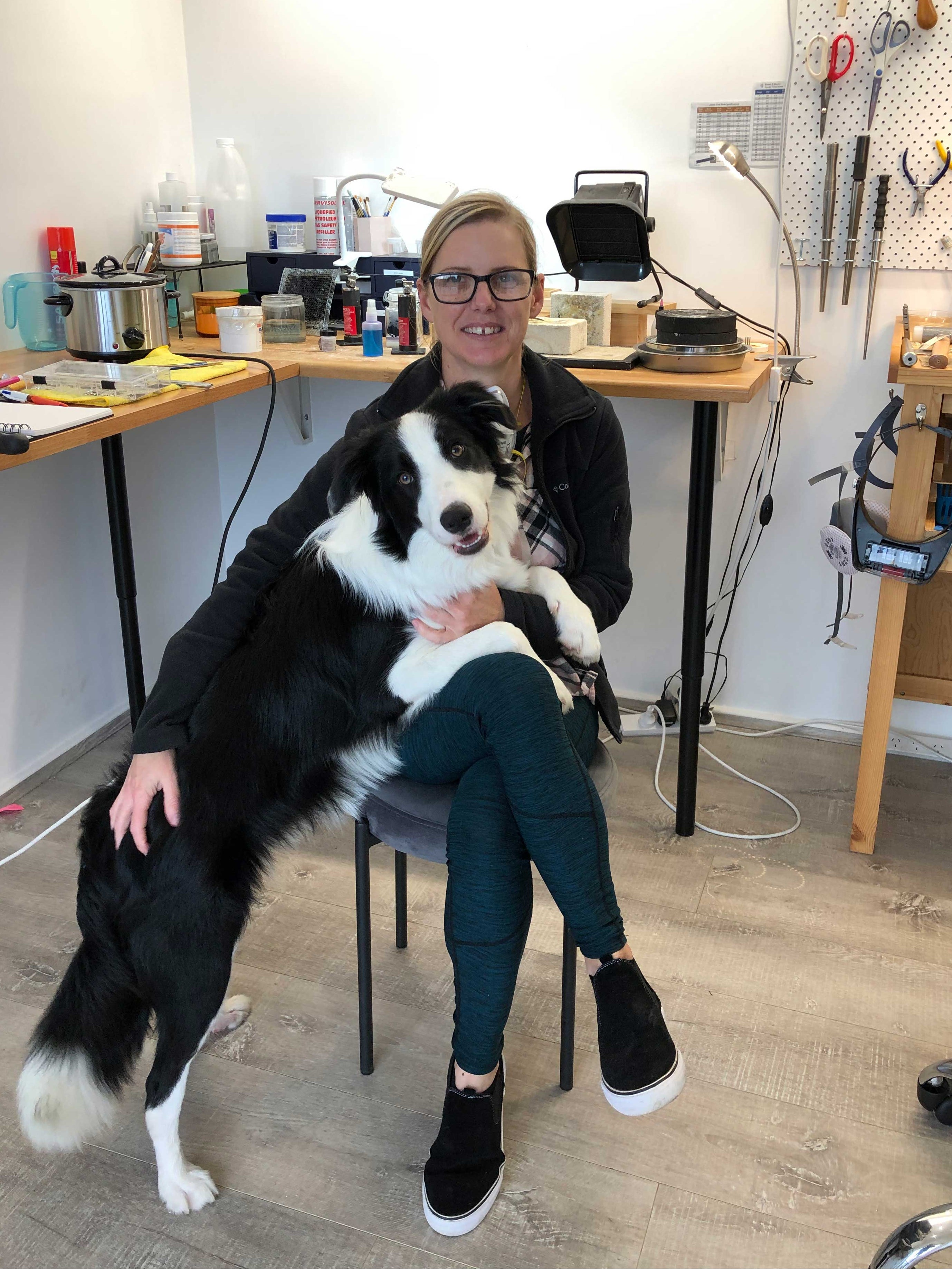 Person sitting on a chair with a black and white dog in a workshop setting