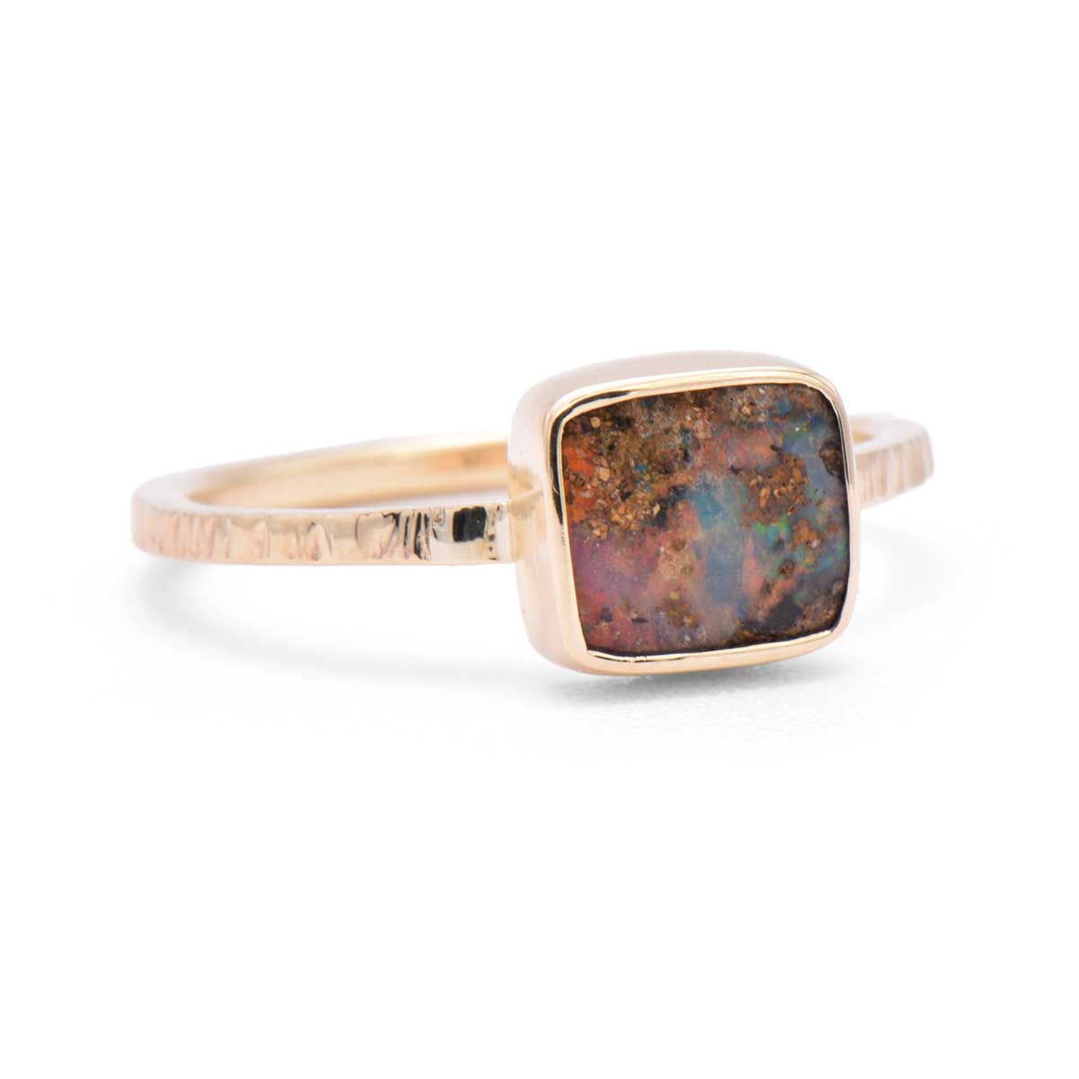 Side view of ORG033 Earth's Secret ring showing boulder opal's earthy matrix in 9K gold setting with distinctive squared profile textured band