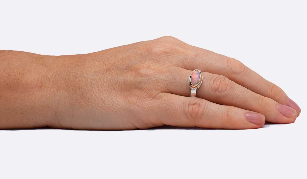 Close-up of oval Coober Pedy opal in Aurora Oval ring (ORMM105) revealing detailed aurora-like colour play and handcrafted 14K gold bezel