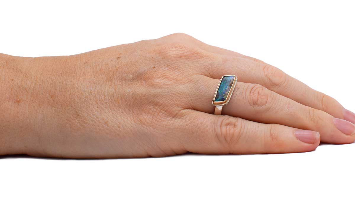 Close-up of parallelogram boulder opal in Coral Geometry ring (ORMM110) revealing detailed blue-green speckles and otherworldly patterns