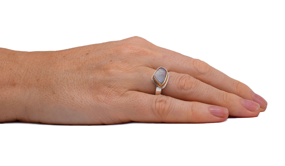 Close-up of triangular boulder opal in Prism Angles ring (ORMM116) revealing detailed rainbow striations and handcrafted 14K gold bezel