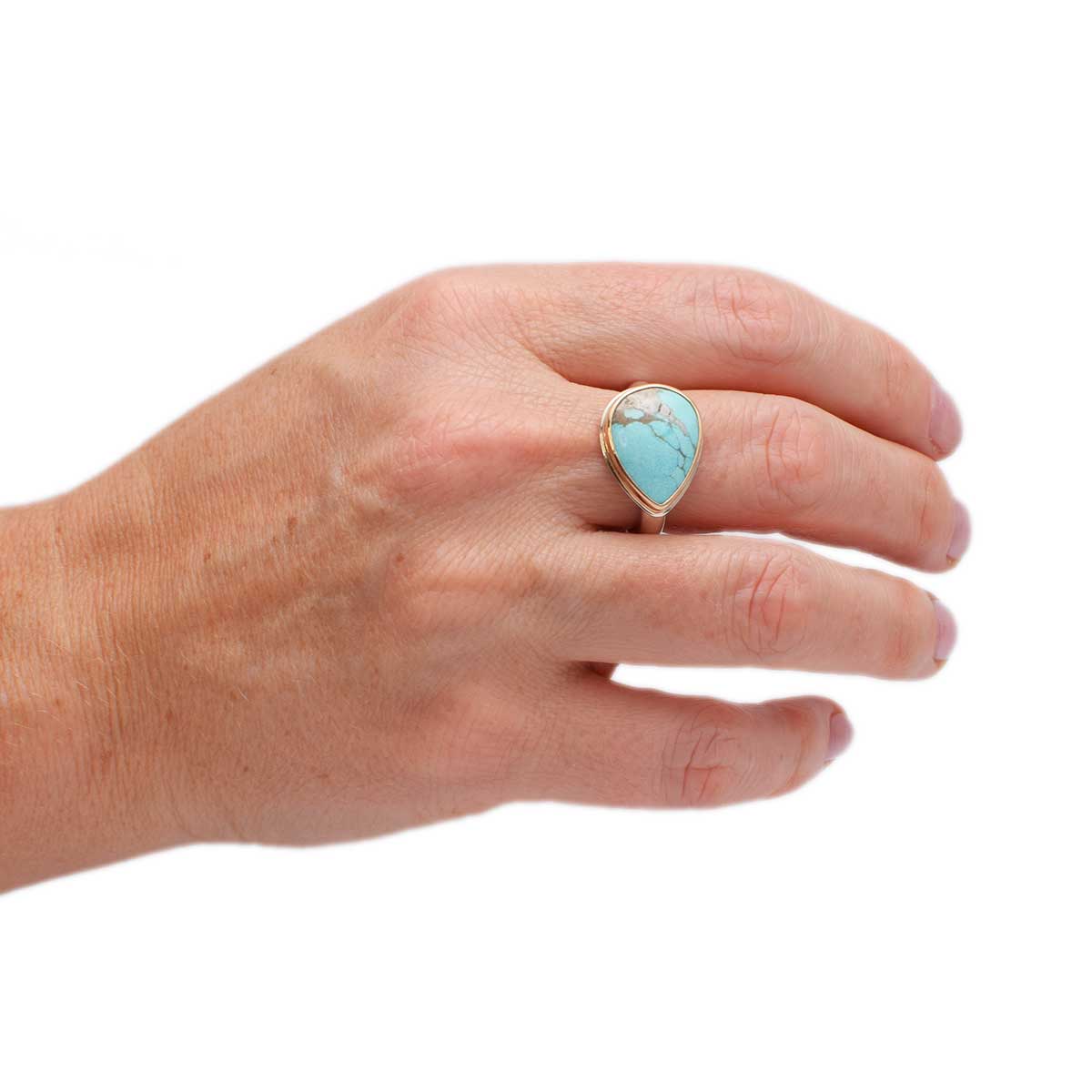 Hand wearing a turquoise ring on a white background