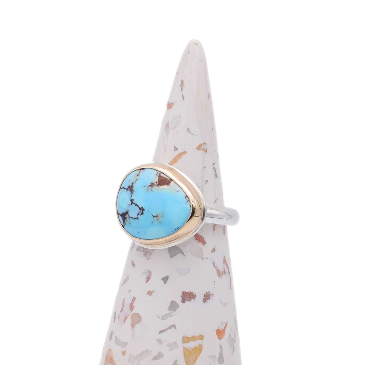 Turquoise ring with silver band on a terrazzo-patterned stand